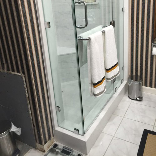 A Picture of a Shower with Towels Hanging On the Door.